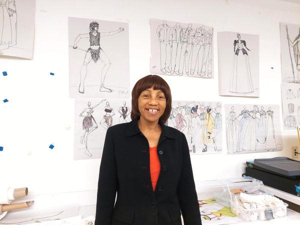 Professor Vera Ashley smiles during class while standing in front of the student illustrations in the fashion classroom, located in the Industry Technology Education Center, on Thursday, April 4.