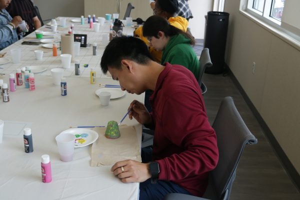 Student Sean Ting, 31, paints a colorful design on his pottery. May 28, 2024. (Joseph Ramirez | The Union)