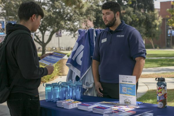 El Camino College hosts campus banner celebration on Oct 10. An Associated Students Organization member informs student about their program near the library. (Susana Reyes | The Union)