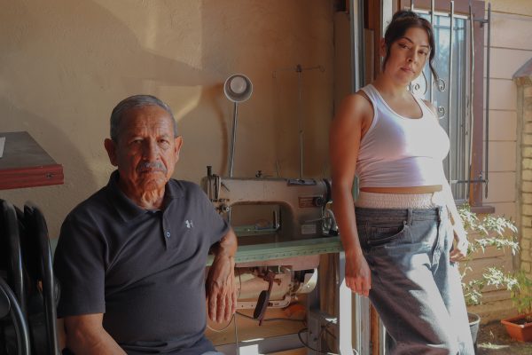 Ashley Mendoza, right, stands next to the Korean-made Sunstar sewing machine and her father, 75-year-old Jose Mendoza, at the Mendoza family’s garage in Compton on Oct. 13, 2024. The sewing machine is 23 years old and was passed down from her father to Ashley Mendoza. “He never left us without clothes and shoes,” Wendy Sufle, Jose Mendoza’s daughter, said. “I remember asking him, how did you meet my mother? And he said, ‘Well, I was the one who would go to their house and do their shoes as well as their clothes,’” Sufle said. (Eddy Cermeno | Warrior Life)