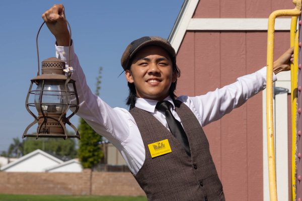 Richard Soriano, 18, hangs off a Southern Pacific caboose at the Lomita Railroad Museum on Oct. 13. Soriano holds a signal lap, which was used by railroad workers to communicate at night. The museum has a collection of several examples. (Katie Gronenthal | Warrior Life)