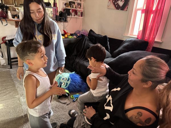 At their home in Inglewood, Calif. on May 1, 2024, El Camino Guardian Scholar Cassandra Gonzalez (right) listens intently to her five-year-old son, Moises "West" Cisneros (left) as her daughter, Elisyannah Valdez, 16, and two-year-old son, Joseph "JJ" Cisneros Struthers, wait patiently. Gonzalez is graduating from ECC on June 7, 2024. Valdez is also graduating this month from high school. (Kim McGill | Warrior Life)