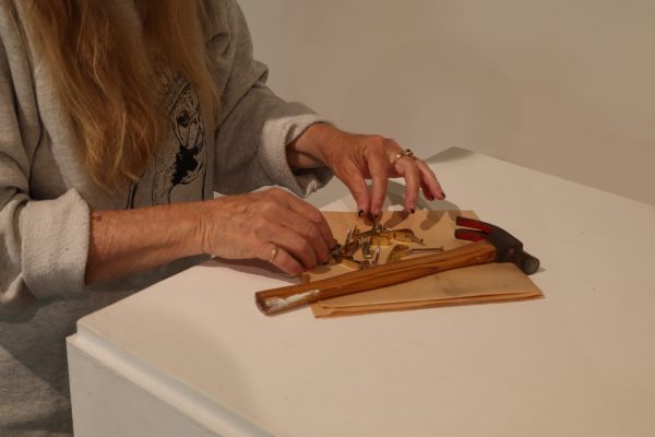 Carrie Lockwood, El Camino College Art Gallery associate, arranges nail hangers that hold up artworks on walls inside the gallery on Wednesday, Oct. 9. After an exhibition is over, Lockwood helps remove nails on the wall where paintings were hung, cleans patches and repaints walls. When patching the walls to repair damages, Lockwood taps a hammer to dent it a bit to then apply spackling paste. Afterward, it is sanded and repainted to look brand new. (Eddy Cermeno | Warrior Life)