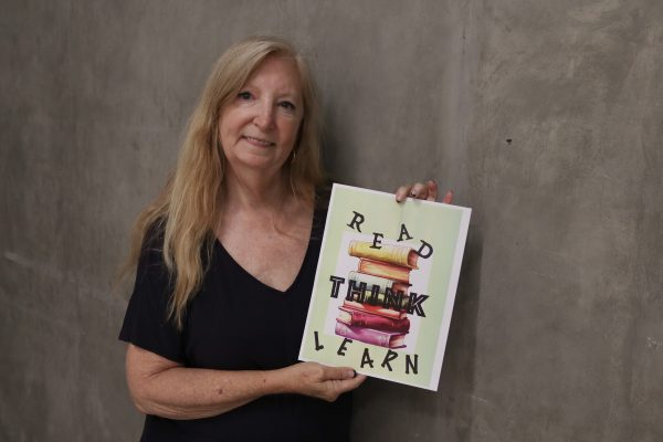 Carrie Lockwood, El Camino College Art Gallery associate, holds a flyer she created inside the Art Gallery on Thursday, Oct. 10.