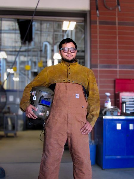 Albert is posing with his passive helmets that are covered and personalized by stickers. | Photo by: Chelsea Alvarez