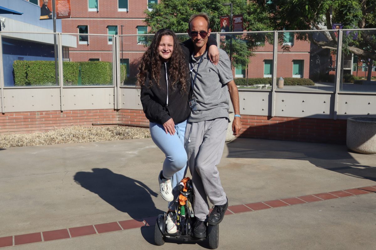 Alex Fleming, 34, and Grace Huntington, 21, ride "Tail" the Segway using "tandem style," a trick they learned shortly after becoming friends outside the Schauerman Library on Sept. 26. (Eddy Cermeno | Warrior Life) Photo credit: Eddy Cermeno