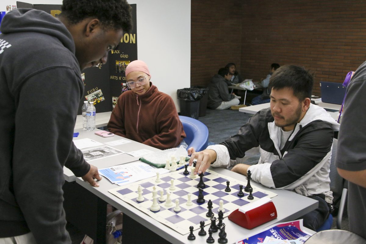 Chess Club president Dang Nguyen makes a move against Black Student Union club member Michael Franck Love while fellow BSU member Carmen Symone watches at Club Rush in the El Camino College Library on Wednesday, March 5.  (Mario Trejos | The Union) Photo credit: Mario Trejos