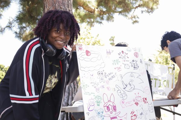 Studio art major Ruth Kembay, 21, promotes a free-draw board for the Art Exhibition Club during Club Rush on Monday, Sept. 8 at the Library Lawn. The club meets Thursdays in the West Library Basement from 1-2 p.m. (Philip Kozel-Lopez | The Union)