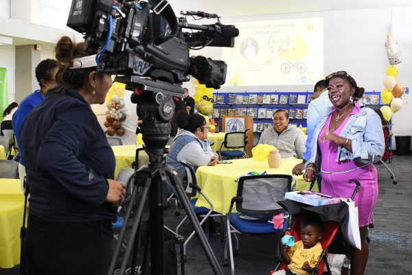 Child development major Denia Baker, 37, is interviewed by NBC4 photographer Azucena Varela during the Parents to Bee community baby shower at the El Camino College Shauerman Library's Collaboration Room on Wednesday, Nov. 19. The event was covered by local news stations including both NBC4 and ABC7. Baker attended with her 16-month-old son, Chozen Taylor. (Nikki Yunker | The Union)