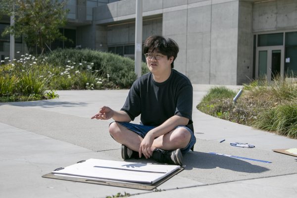 Eugene Choi, 19, sits on the concrete floor in front of the El Camino College Arts Complex building on  (Frances Que | the Union)