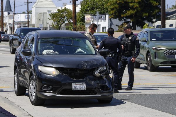 Highway Patrol Officer B. Thomas talks to first response police officers at the scene of the car collision. (Matthew Beck | The Union)