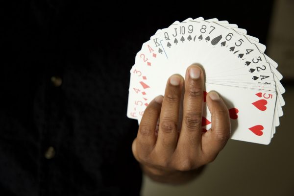 El Camino College law professor Nicholas McGrue, 42, fans playing cards by his office in the Math, Business and Allied Health Building. McGrue practices card tricks, rubber band magic and mentalism. (Nikki Yunker | Warrior Life)